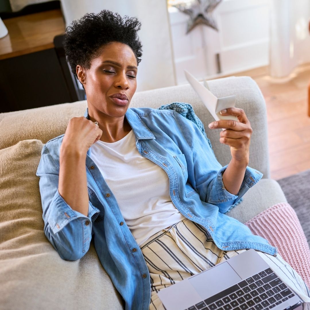 woman sitting in daylight living room fanning herself due to a hot flash