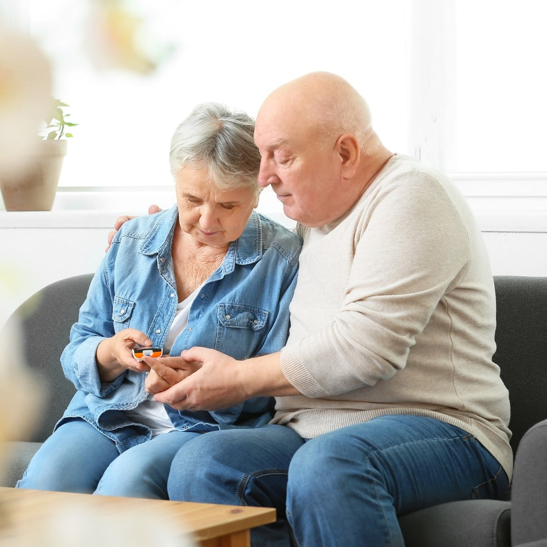 two adults sitting and looking at blood sugar monitor