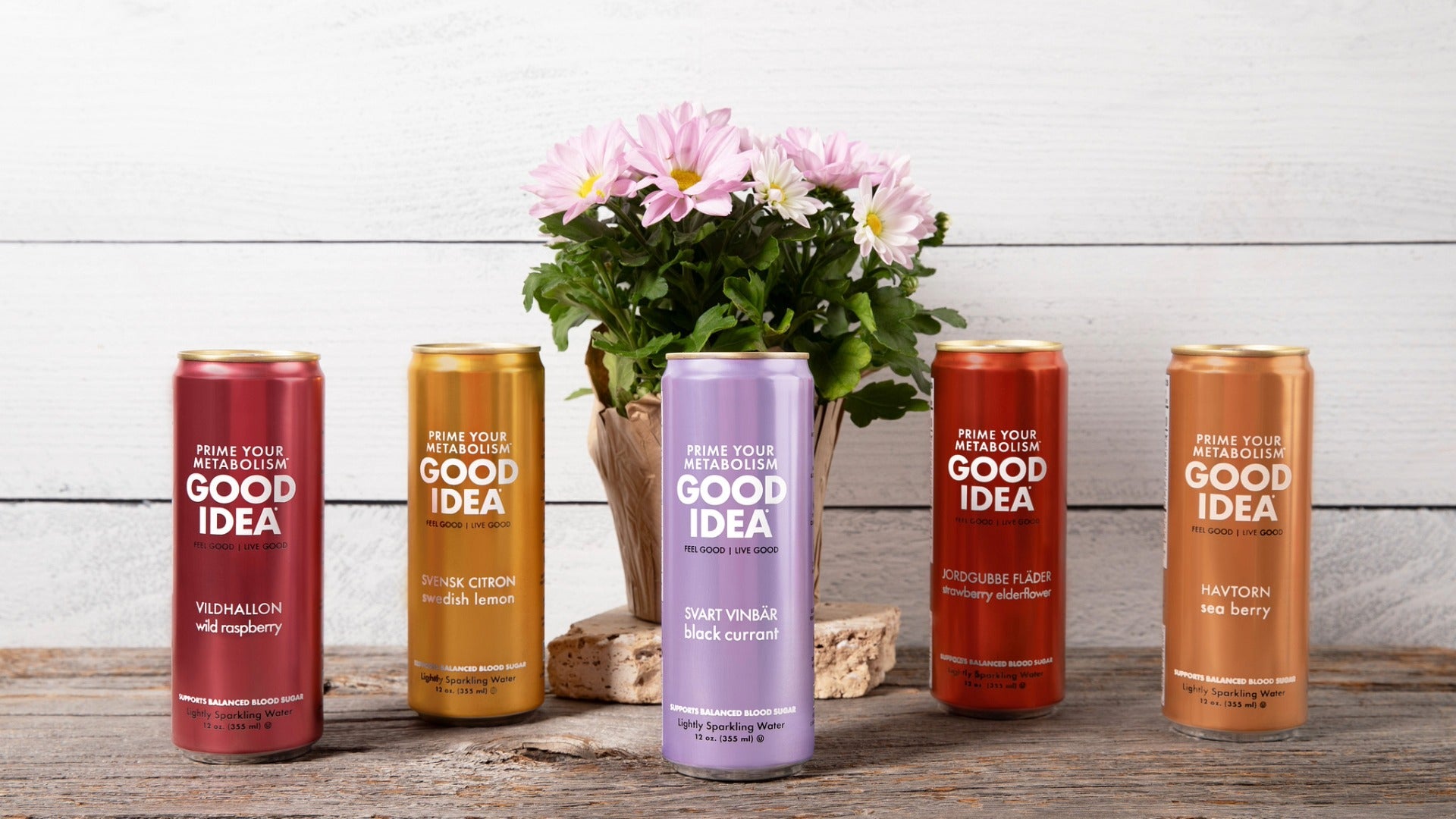 All five flavors of GOOD IDEA on a wooden countertop with flowers in the background