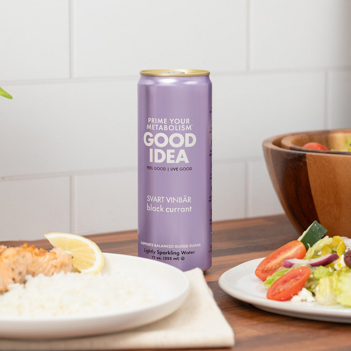 Can of Good Idea sparkling water with a salad and salmon dish on a table.