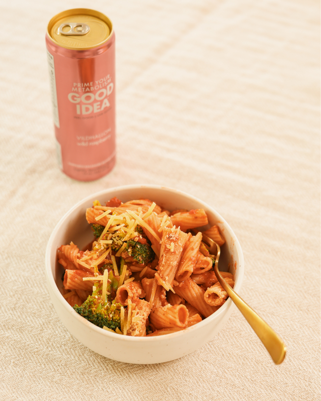 Bowl of pasta with broccoli and a can of GOOD IDEA next to it