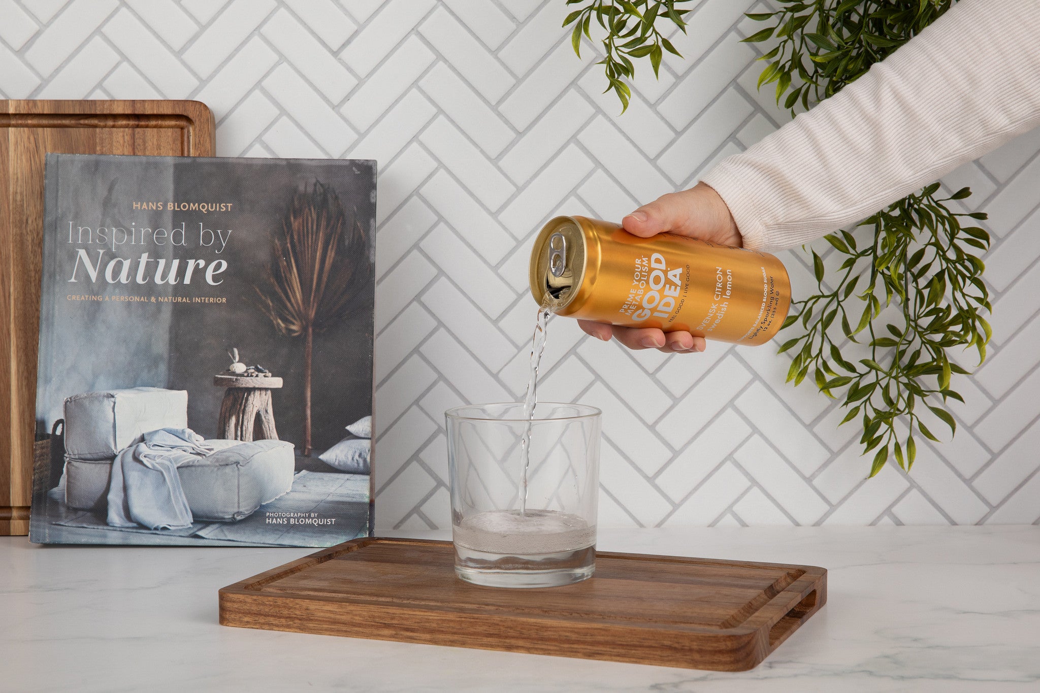 Person pouring a can of Good Idea sparkling water into a glass on a kitchen counter