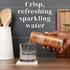 Person pouring a can of GOOD IDEA Sea Berry sparkling water into a glass on a kitchen counter, with text on the image that reads “crisp, refreshing sparkling water.”