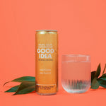 Can of Good Idea Sea Berry sparkling water with a glass of sparkling water on an orange background