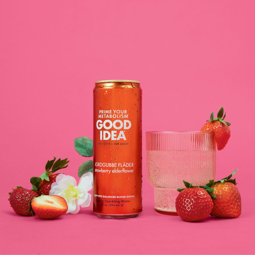 Can of GOOD IDEA Strawberry Elderflower sparkling water with a glass of sparkling water and fresh strawberries beside it.