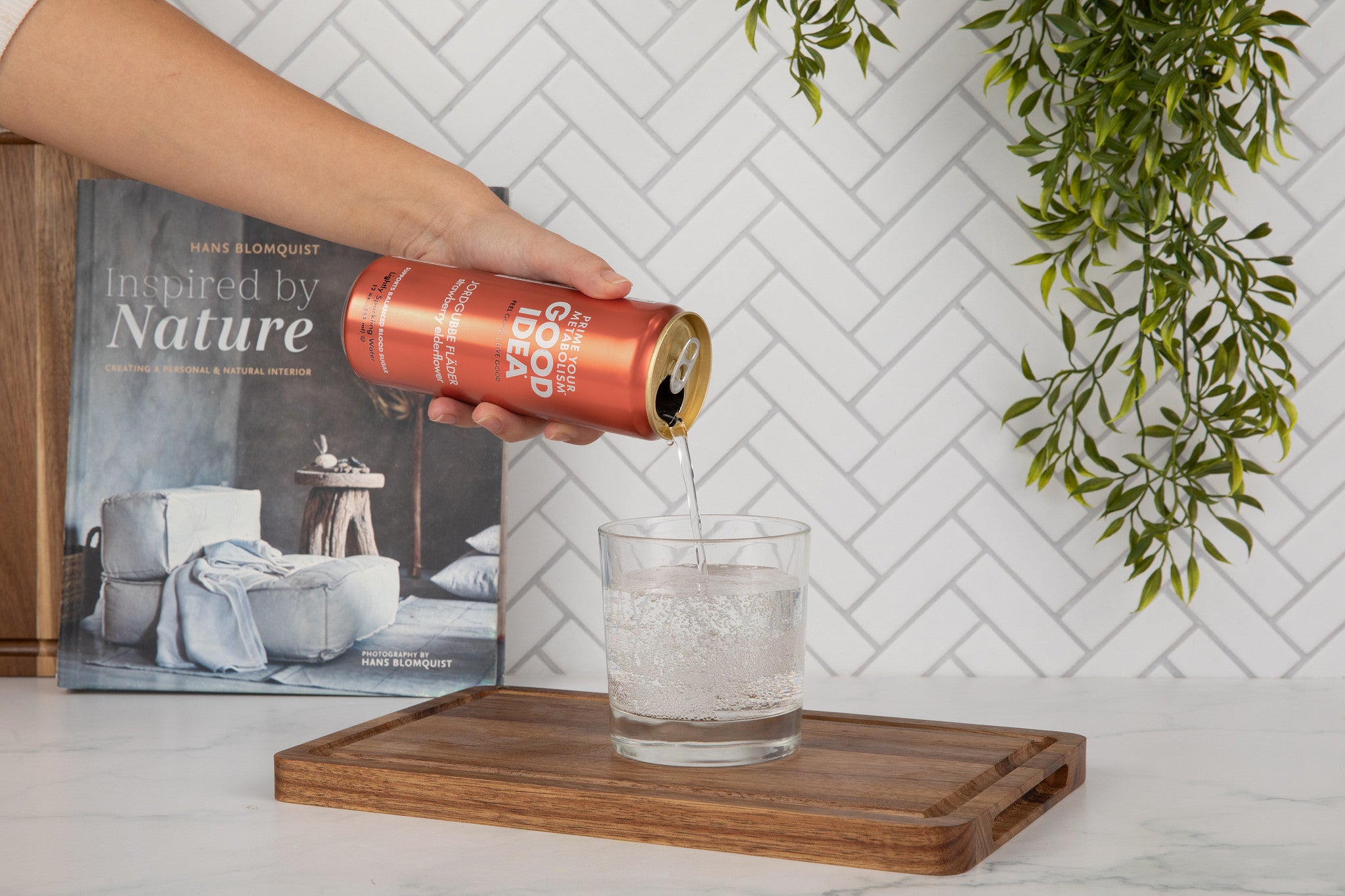 Person pouring a can of Good Idea Strawberry Elderflower sparkling water into a glass 